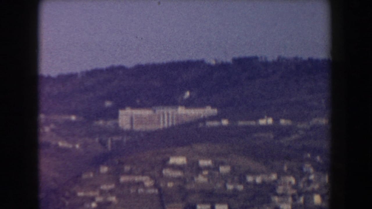 Distant hillside town with a large pale building under a hazy sky.