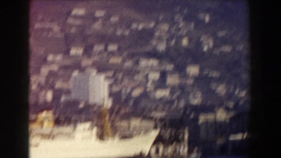 1959 Pisa, Italy travel frame with a soft, elevated view across dense town buildings and a bright foreground slope.
