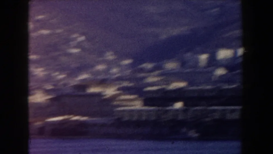 1959 Pisa, Italy 8mm frame showing a blurred pan across blue water toward distant buildings on a hillside.