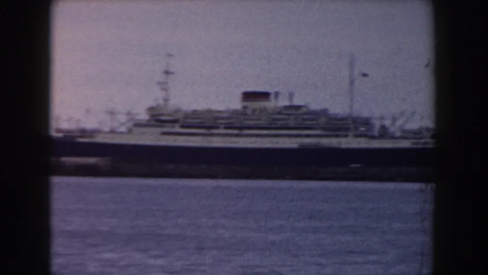 A large passenger ship in Pisa, Italy, 1959, remains across the harbor, partially divided by dark foreground framing.