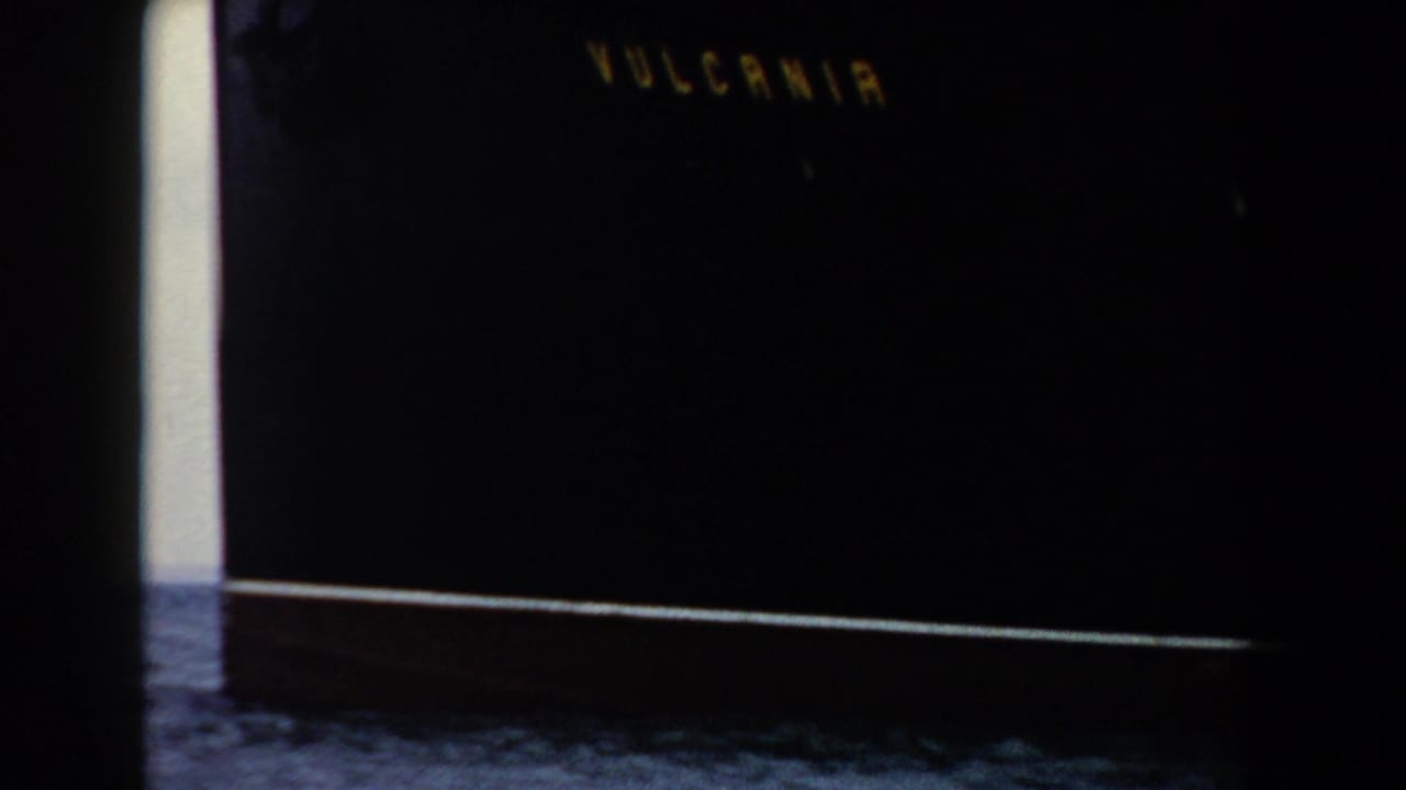 1959 Pisa-area home-movie frame with dark exposure, faint lettering, a bright edge, and indistinct foreground detail.