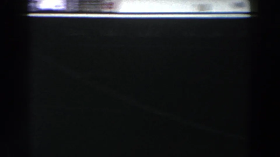 Dark, blue-tinted 8mm frame with soft blur and a pale horizontal band, with few identifiable details visible.