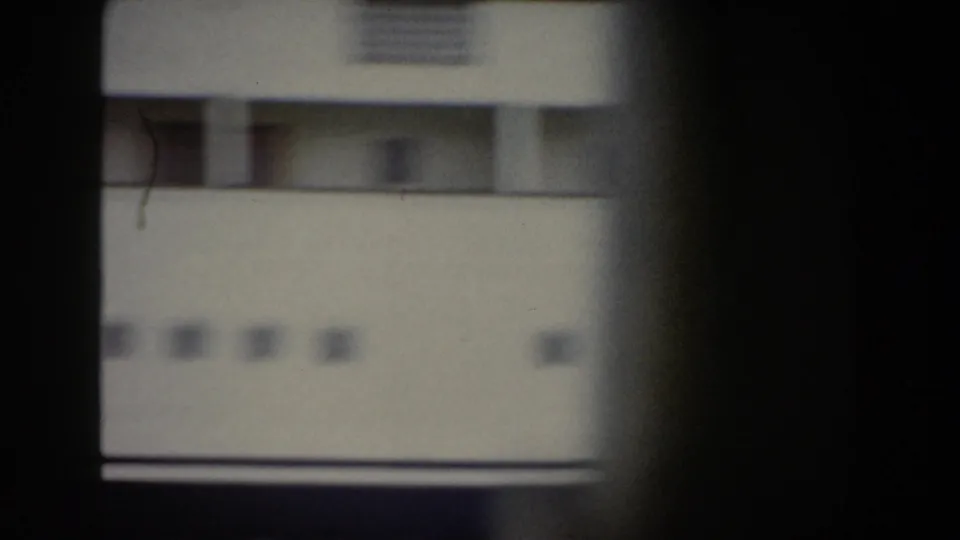 A white ship wall and windows appear in dark 1959 Italy home-movie footage, partly blocked by a vertical foreground shape.