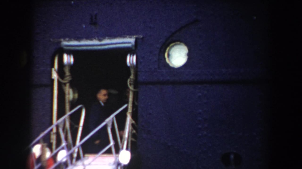 Open aircraft doorway with a metal gangway and a person standing inside at night.