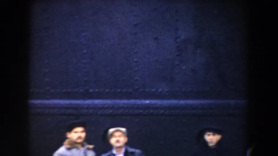 In 1959 Pisa home-movie footage, small standing figures appear beneath dark vertical framing near a wharf or large vessel.