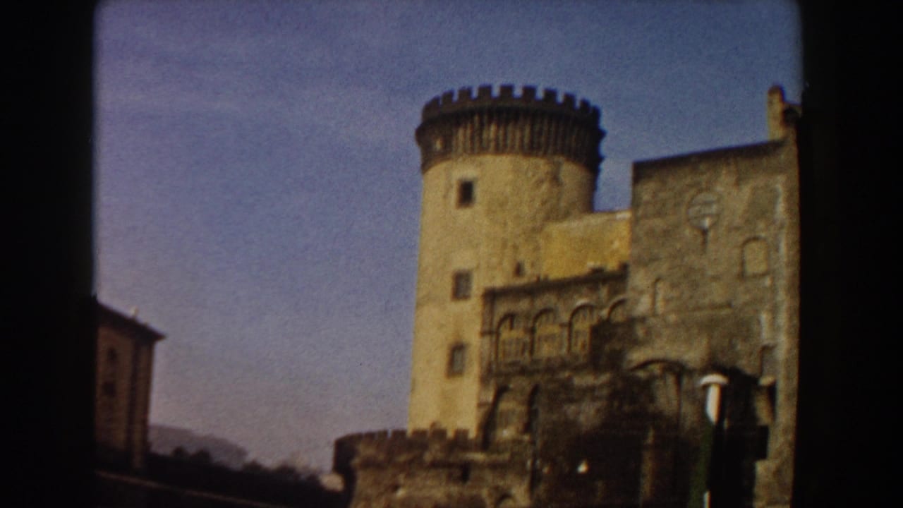 Stone castle tower and battlements under blue sky, framed by dark 8mm borders.