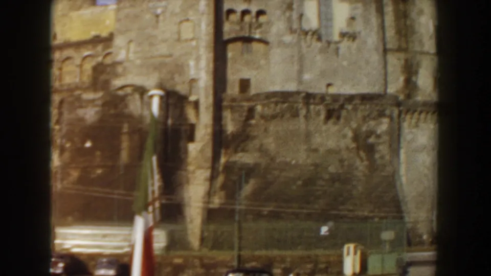 The final 1959 Pisa frame shows the castle wall, flagpole, lamps, fencing, and cars with visible grain and warm faded color.