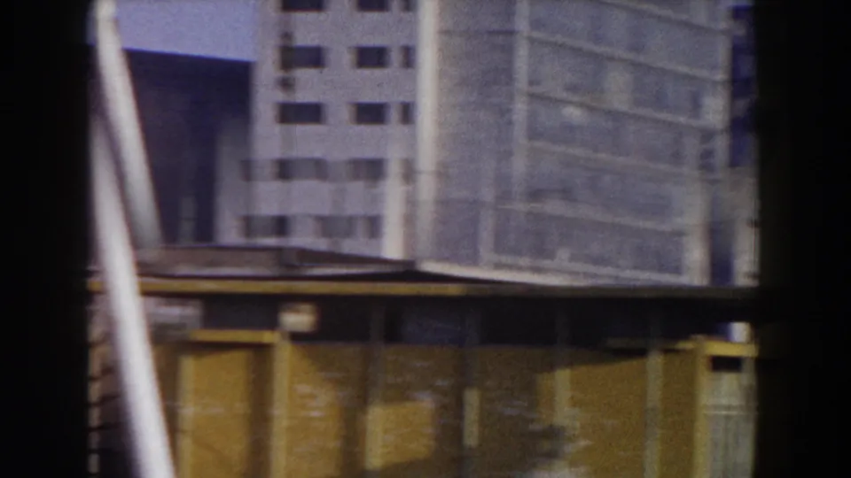 Modern Pisa buildings and a yellow foreground structure appear in a blurred 1959 8mm travel shot.