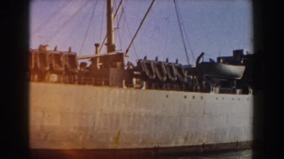 Docked cargo ship in Pisa, Italy, seen with warm 8mm light leak across the pale hull, deck equipment, and rigging.