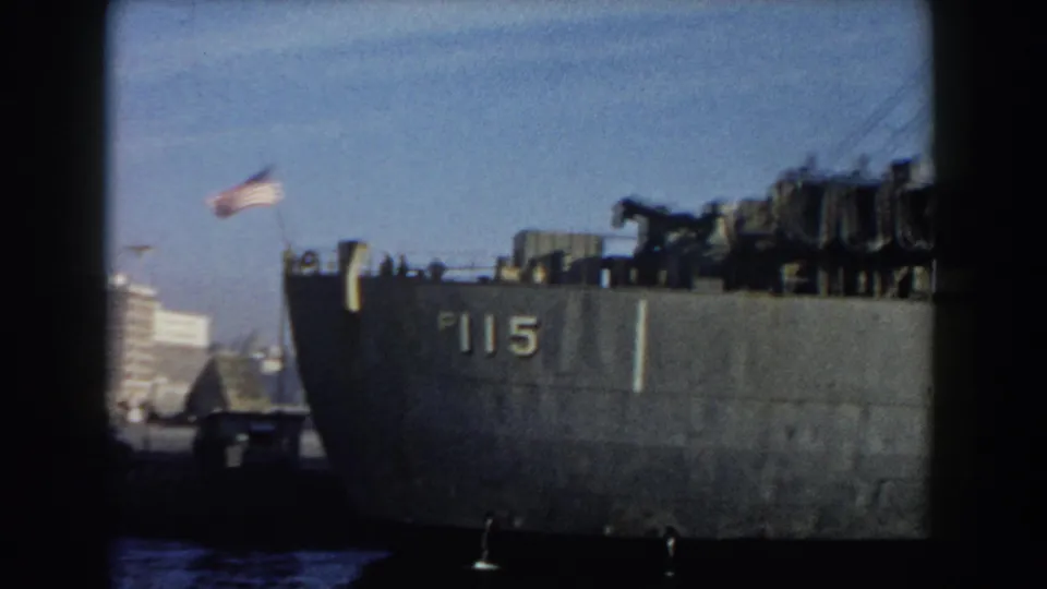The final 1959 Pisa frame holds on the P115-marked ship, with an American flag, deck equipment, harbor water, and dark 8mm frame edges visible.