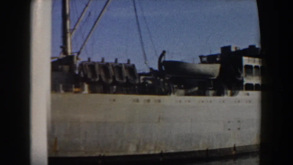 Final frame of the 1959 harbor clip showing more of the military ship's upper deck, mast and rigging in faded 8mm color.