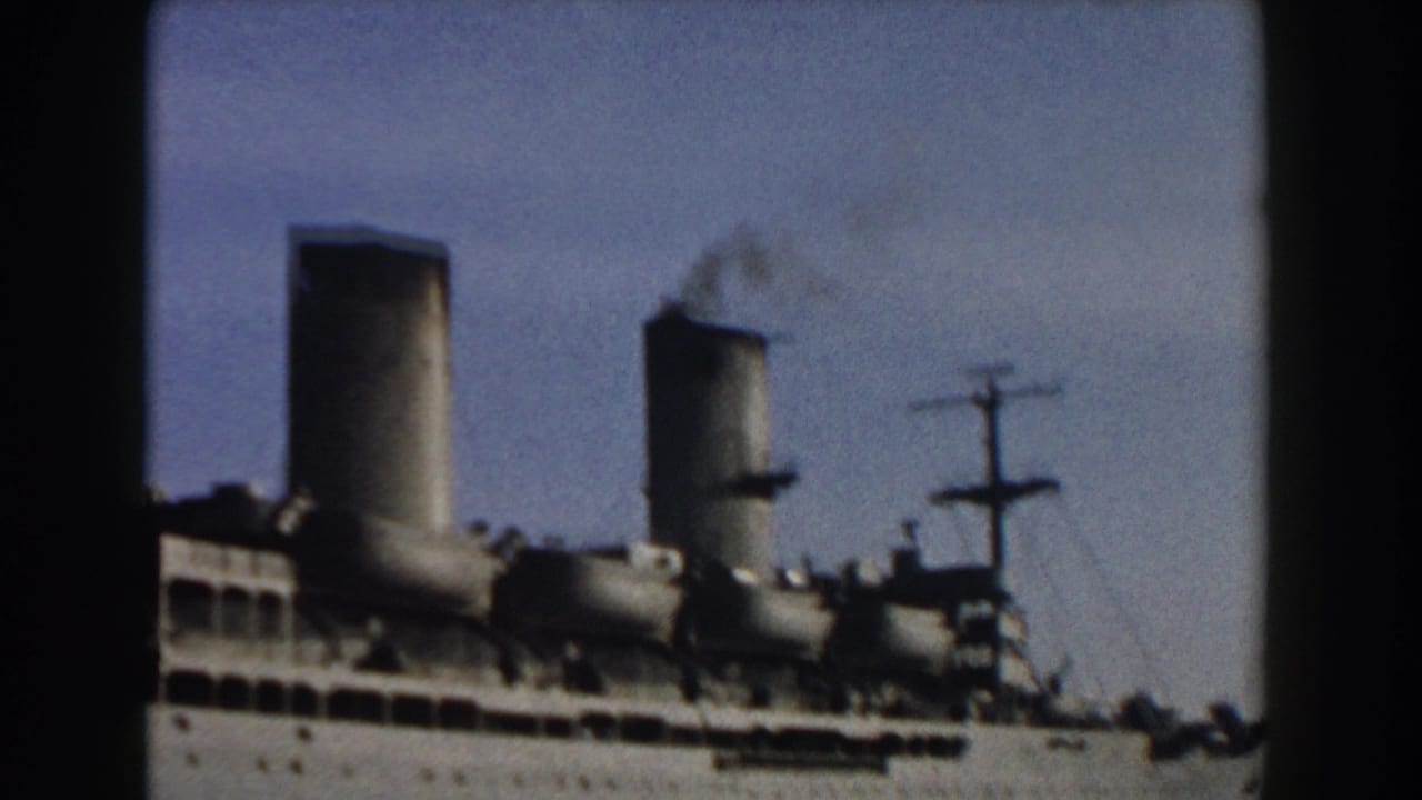 1959 Pisa, Italy home-movie frame showing a white passenger ship with twin smokestacks, faint smoke, and water in the foreground.