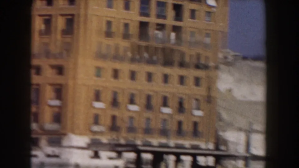 1959 Pisa street frontage with a tall ocher apartment block, balconies, and adjacent worn plaster walls.