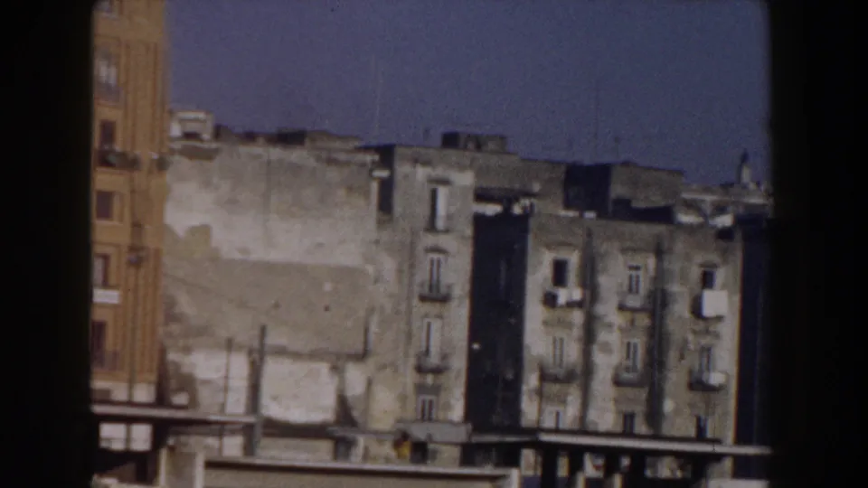 1959 Pisa urban street scene with worn facades, balconies, and mid-century vehicles near the lower edge.