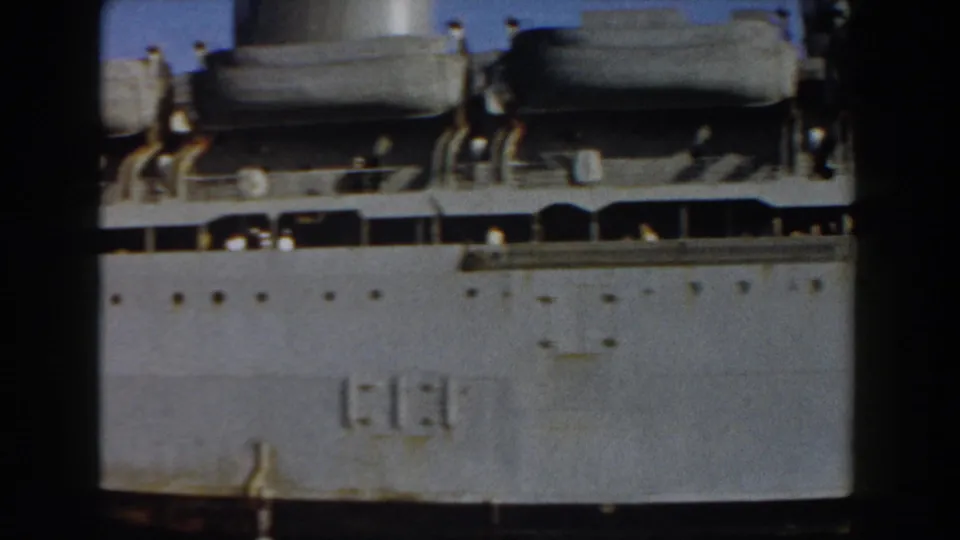 Large vessel seen in Pisa-area home-movie footage, with lifeboats, railings and small people along the side.