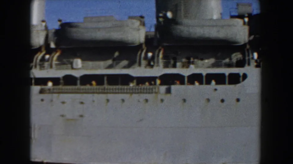 Pisa, Italy 1959 footage showing the side of a large vessel with lifeboats, portholes and small figures on deck.