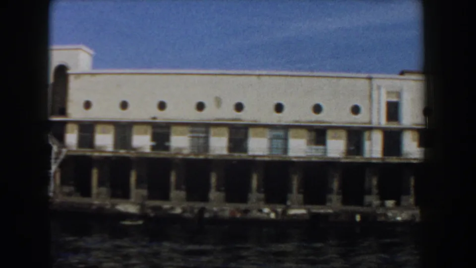 Final boat-shot view of the Pisa waterfront facade, with a row of circular windows above dark pier supports and water below.