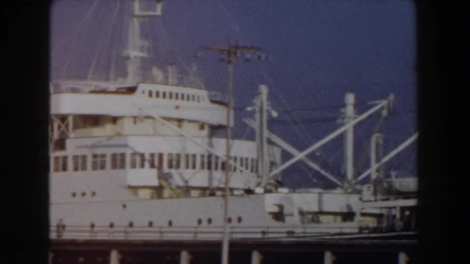 1959 Pisa, Italy view of a docked passenger ship superstructure with rows of windows, masts, railings, and foreground utility pole.