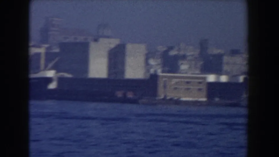 A large vessel appears along the Pisa waterfront, with blocky harbor structures and water visible through the 8mm frame.