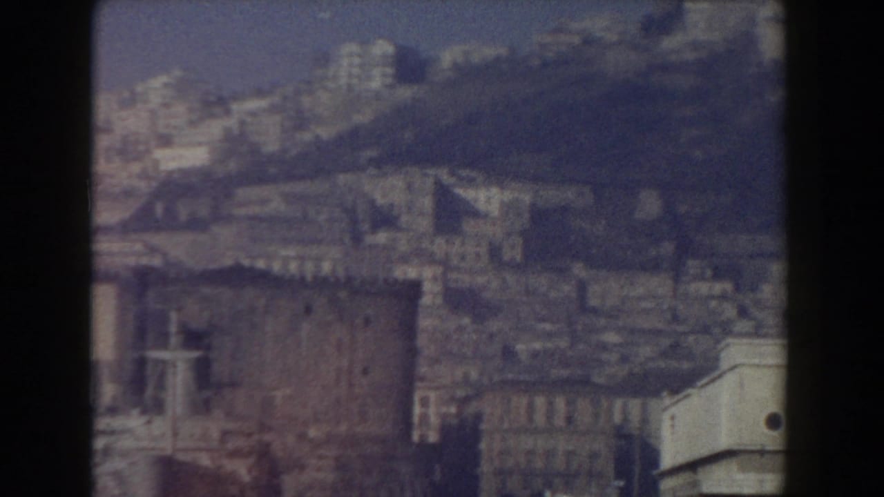 Distant hazy cityscape with historic buildings and dark film borders.