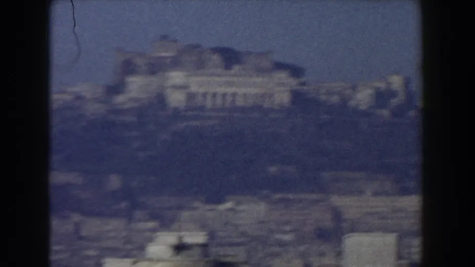 1959 Pisa travel footage frame with pale monumental buildings and surrounding rooftops softened by haze.