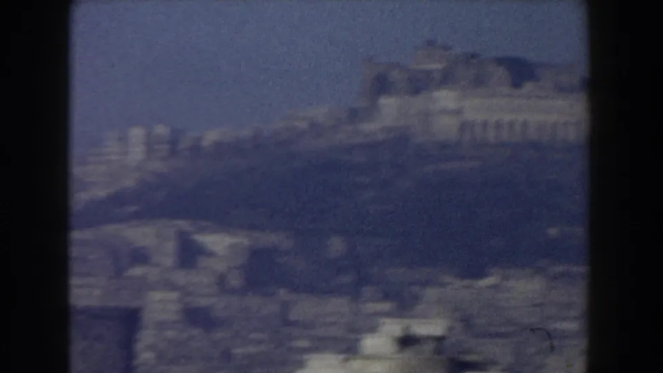 Pisa, Italy, 1959, seen as a grainy 8mm city view with pale architecture beyond foreground rooftops.