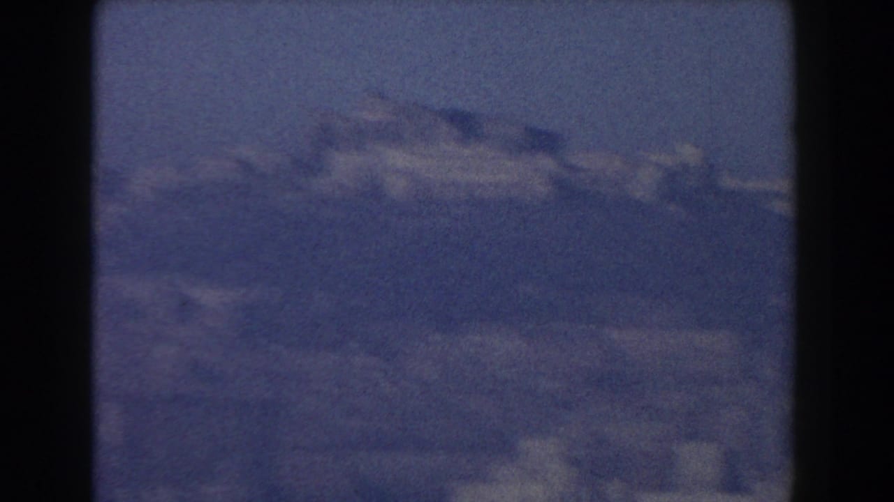Hazy distant hills and pale buildings seen through a dark-framed view.