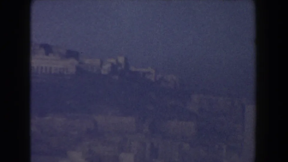 Distant Pisa hillside buildings appear through haze and soft focus, divided by a dark vertical frame edge.