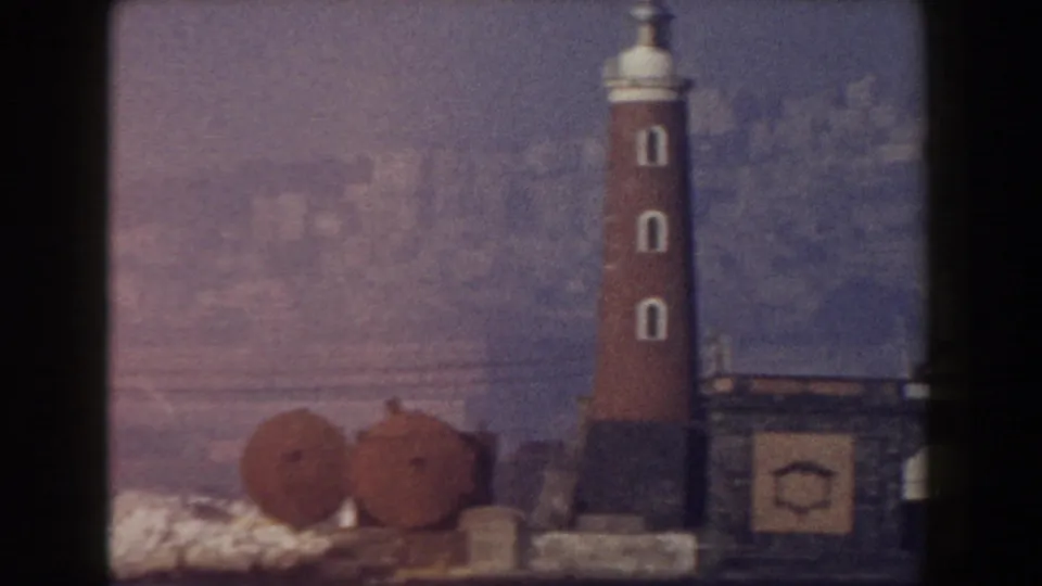The Leaning Tower of Pisa appears in a soft, grainy 1959 8mm view with rooftops and distant buildings.