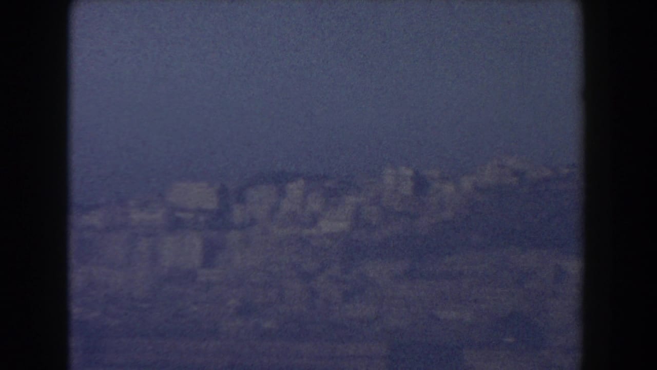 Hazy distant city and hillside seen through dark 8mm frame borders.