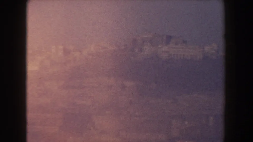 Final 8mm frame of a hazy hillside and distant city near Pisa, Italy, tinted by warm exposure variation.