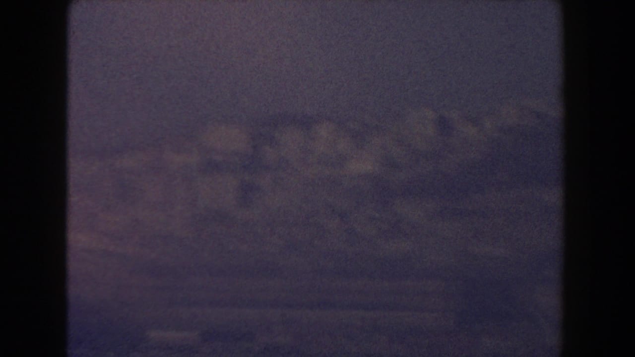 Dark-framed hazy view of faint distant buildings under a muted sky.