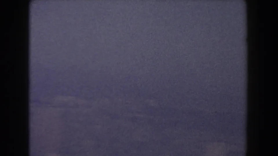 Late frame from the 1959 Pisa 8mm clip with blue-gray haze, weak distant landscape detail, dark border, and pronounced film grain.