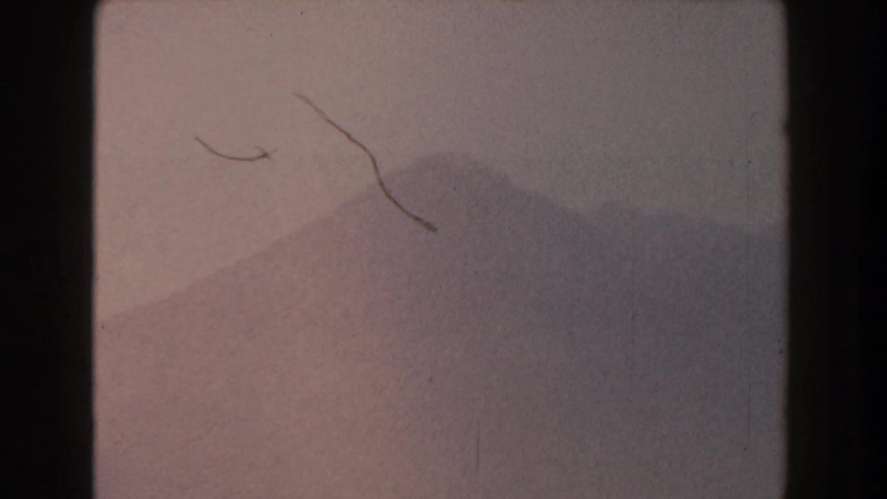 Hazy mountain silhouette with pale sky and visible film edges.