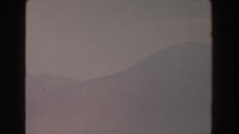 1959 Pisa, Italy 8mm frame with a muted mountain profile emerging through haze, framed by dark scan borders and light film wear.