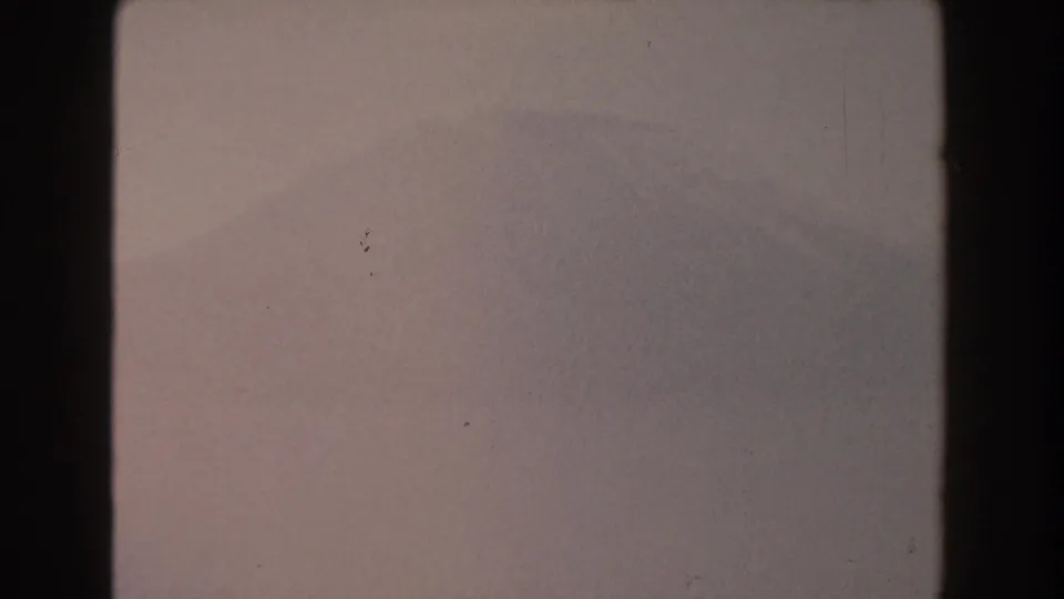 1959 Pisa, Italy 8mm frame with a faint distant mountain silhouette, subdued pink-gray color, soft focus, and scattered dust marks.