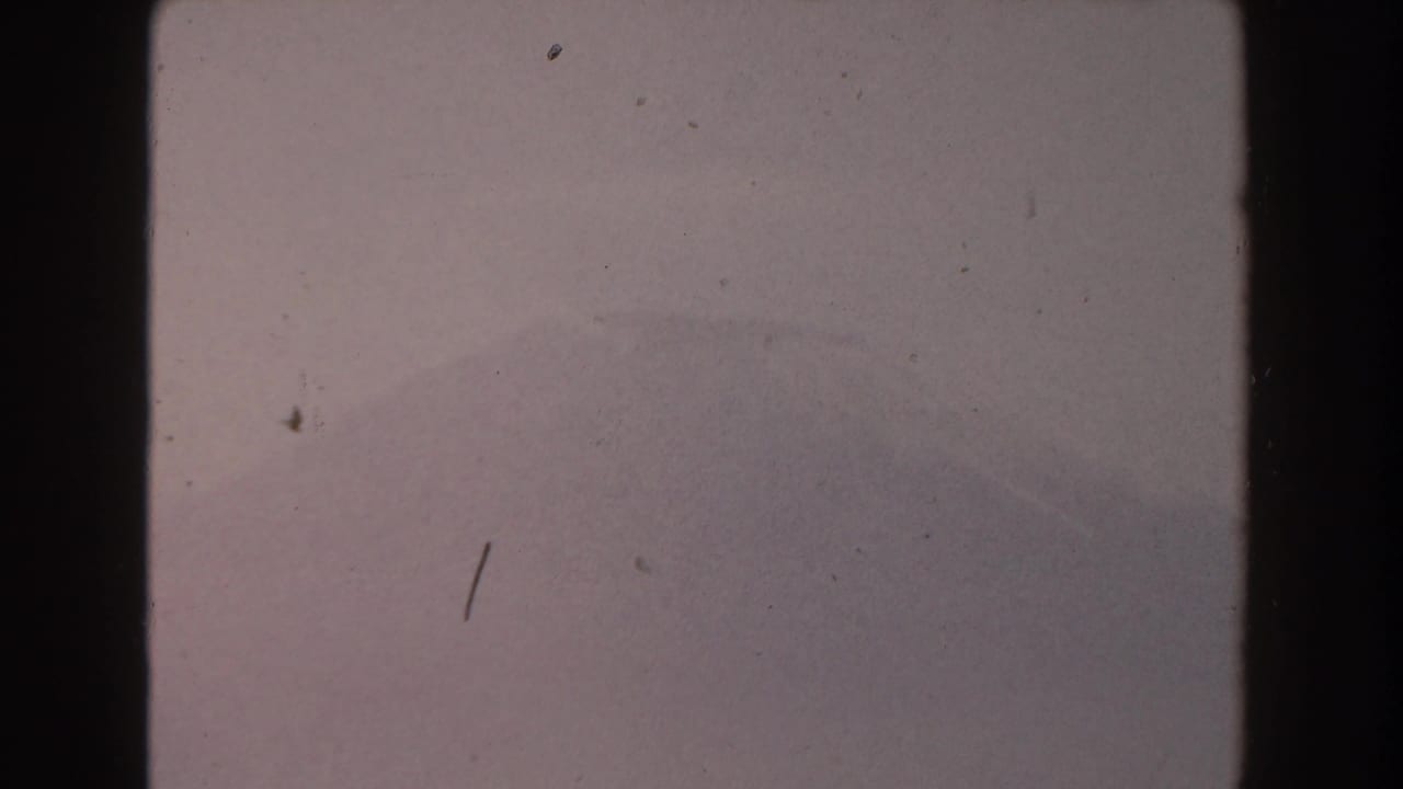 Pale cloudy sky with faint distant landform and visible 8mm frame borders.