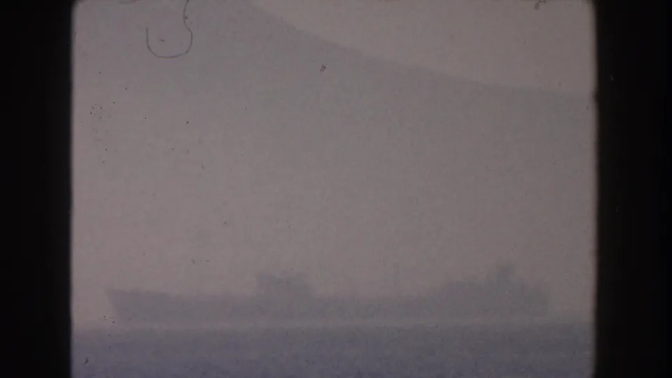 The 8mm frame holds on a muted Pisa horizon, with faint land or mountain shapes softened by haze and visible film dust.