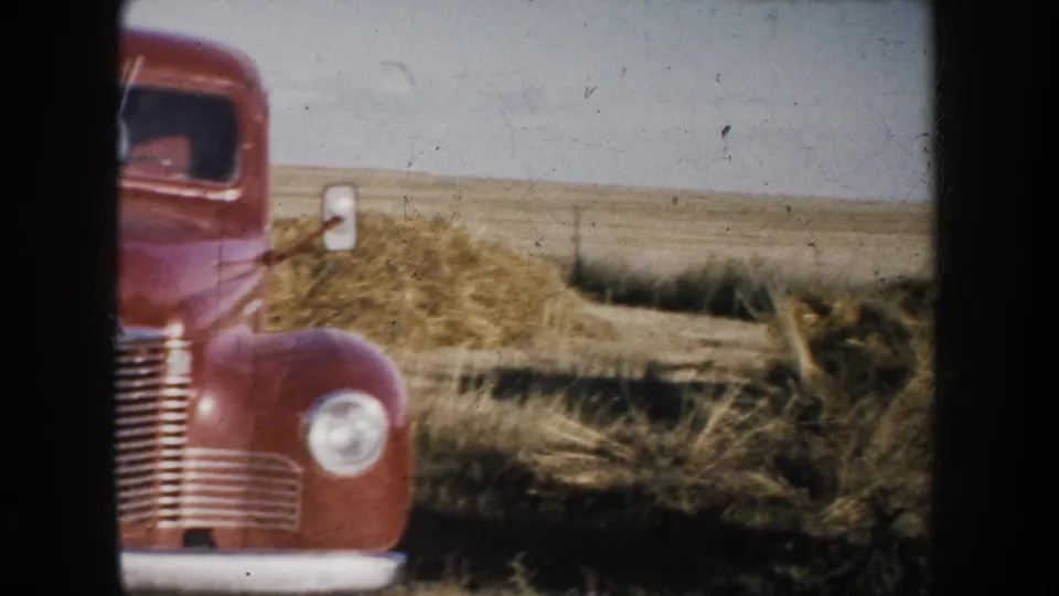A red truck comes into view near the horse and man, with dry grass and flat South Dakota prairie stretching behind it.