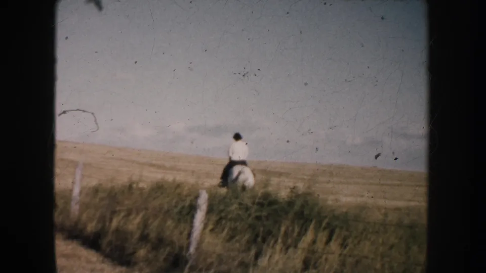 A distant view shows the woman and horse moving away behind tall grass, framed by 8mm film borders and a wide South Dakota horizon.