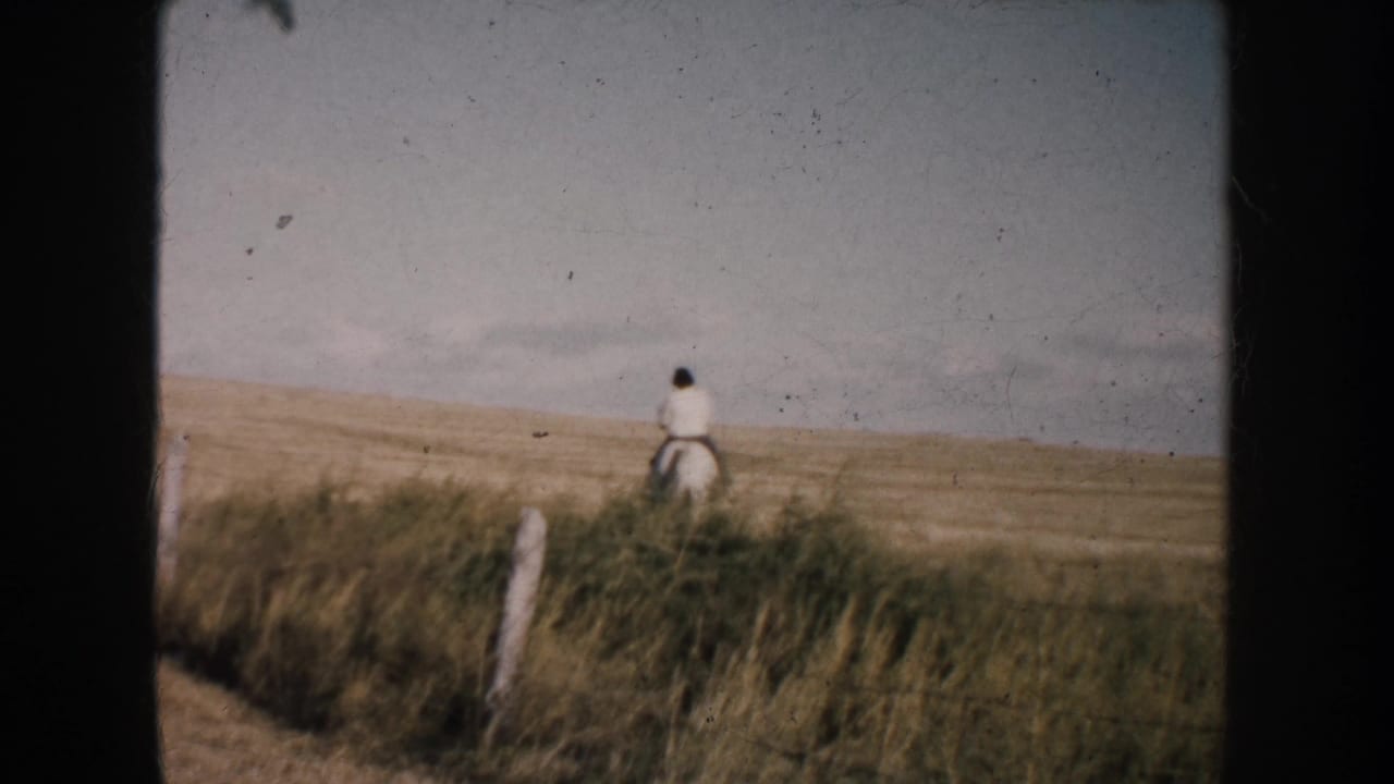 In 1953 South Dakota home-movie footage, a woman rides a horse away across open prairie near a simple fence line.