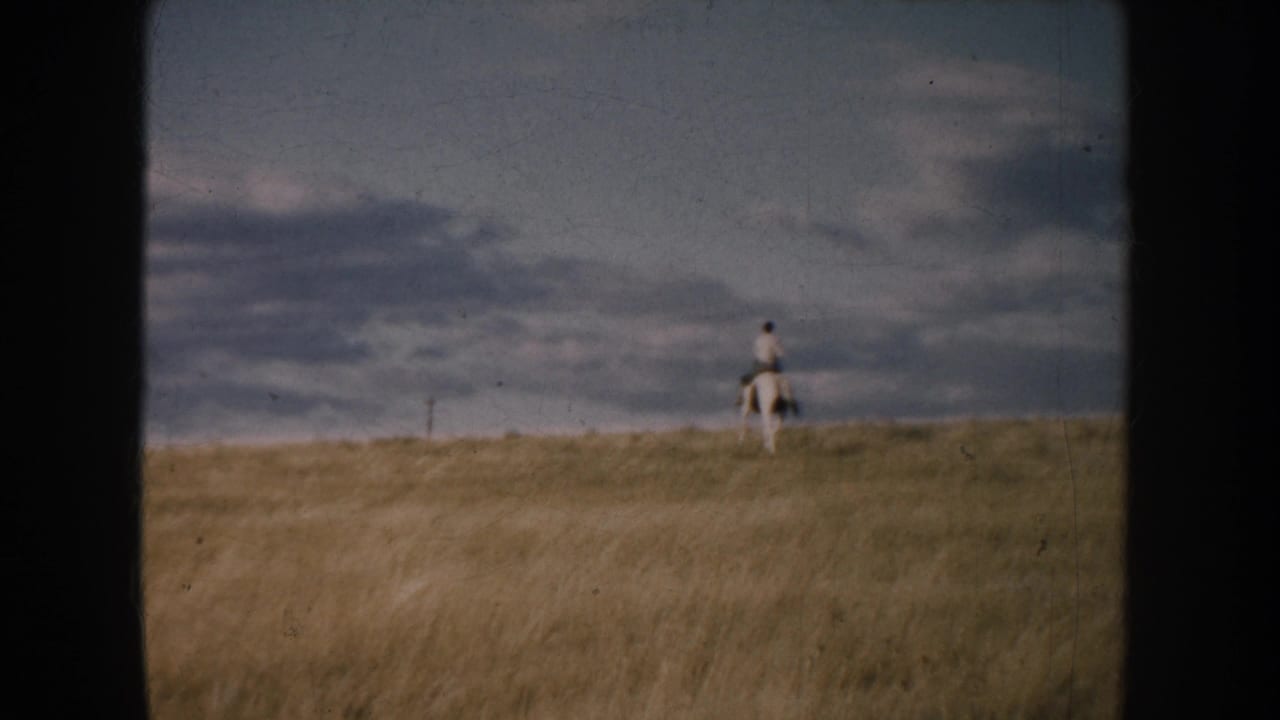 1953 South Dakota 8mm frame showing a distant lone rider on horseback on open grassland under clouds.