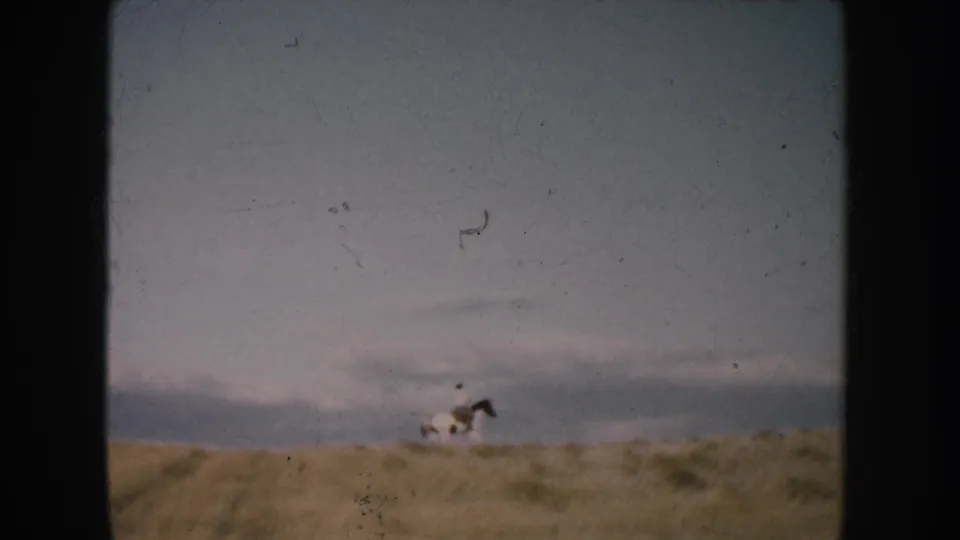 Soft 8mm frame of a distant rider on horseback along a South Dakota prairie ridge in 1953.