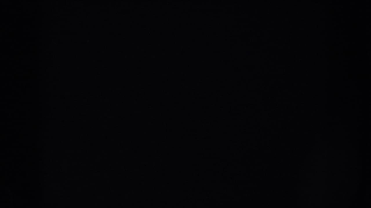 Mostly dark frame with faint film texture and no clear subject.