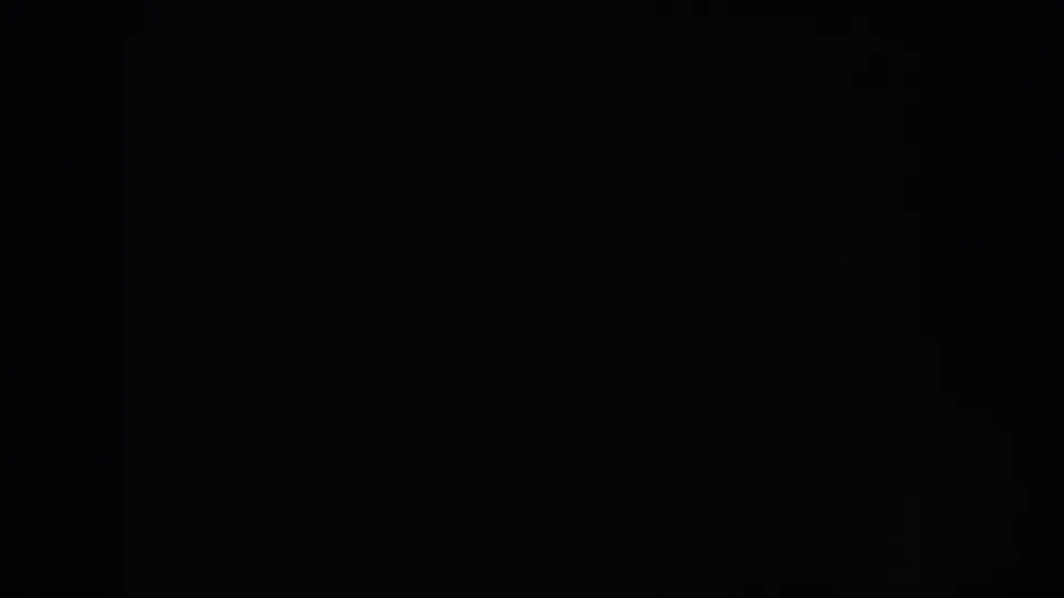 Mostly dark 8mm frame with a partial bright view at the right edge, likely just before the car scene becomes clear.
