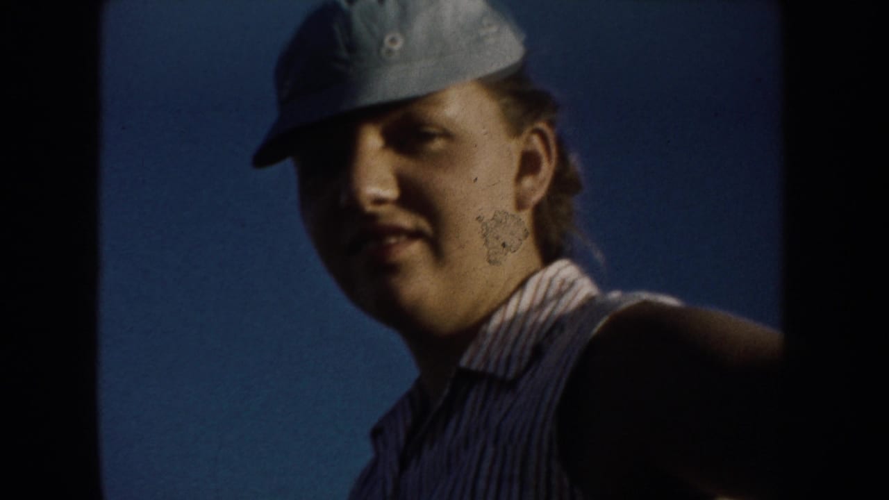 Close view of a young woman in a light cap and sleeveless striped shirt against a blue sky.