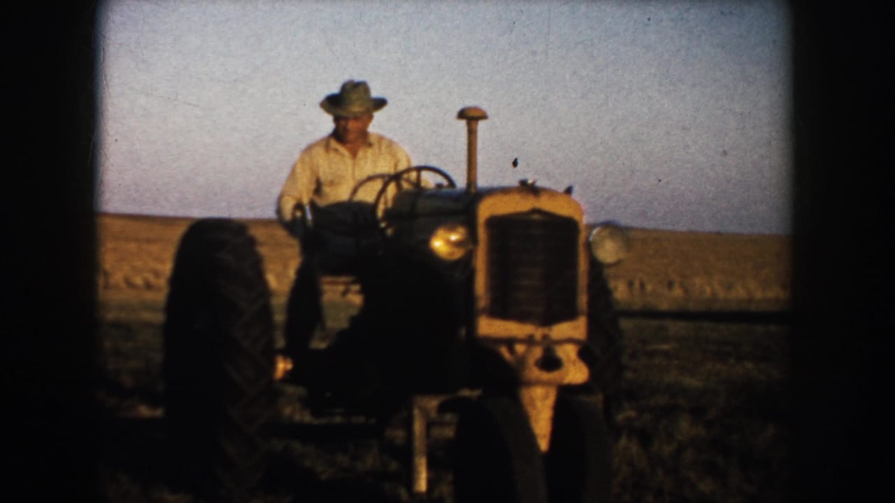 Farmer in a brimmed hat drives an older tractor through a South Dakota field in 1953 home-movie footage.