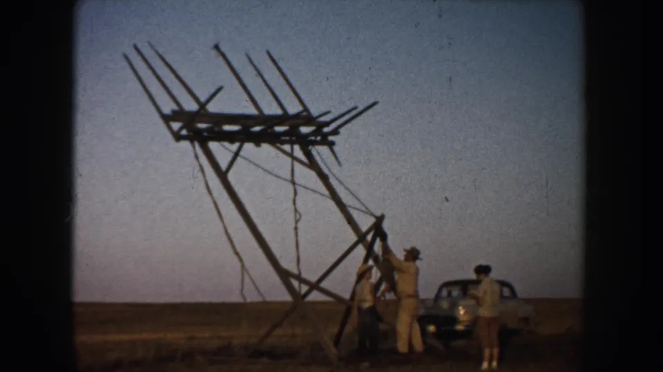 Near the end of the clip, men cluster around the base of the leaning sign frame in the rural South Dakota field with the car beside them.
