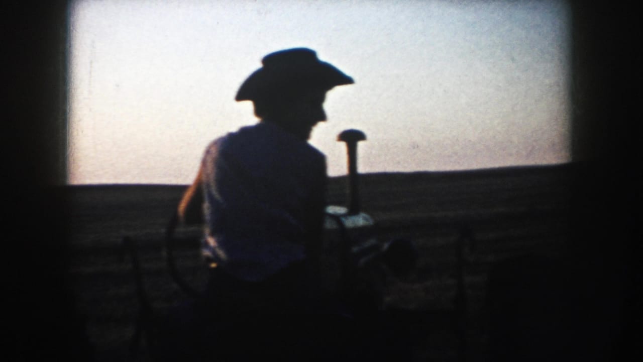 A silhouetted tractor operator appears in profile on South Dakota farmland, with the horizon and dusk sky behind.