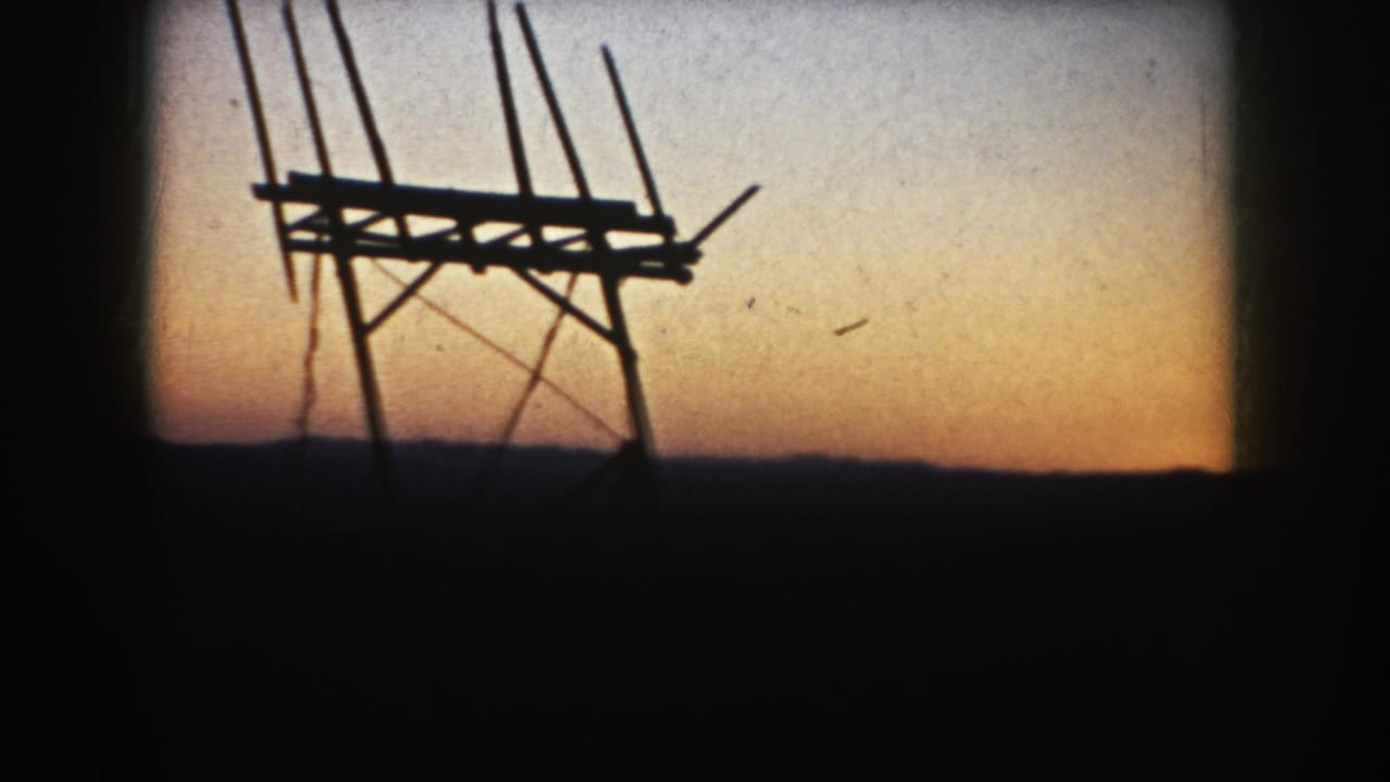 The final 8mm frame shows a silhouetted wooden farm structure on open South Dakota farmland under fading evening light.
